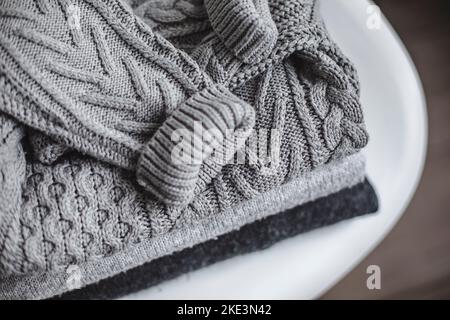 Kuschelige, graue, warme Pullover auf dem Stuhl. Konzept Herbst Winter Stockfoto
