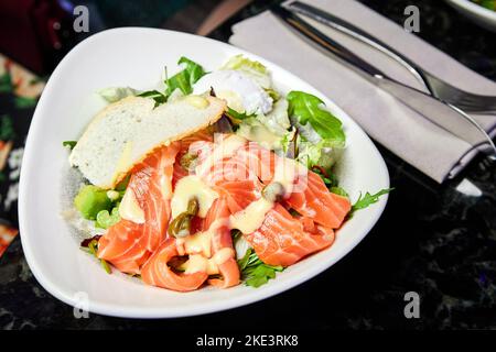 Salat aus norwegischem Lachs, pochiertem Ei und Sauce Hollandaise Stockfoto