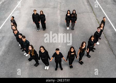 Ivano-Frankivsk, Ukraine 15. Mai 2021: Foto von Studenten, die auf dem Schulhof ein Smiley machten, Studenten in schwarzer Kleidung, einem lustigen Smiley und Studenten. Stockfoto