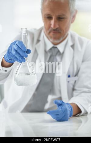 Ein Forscher, der in einem Labor mit Bechergläsern arbeitet. Stockfoto