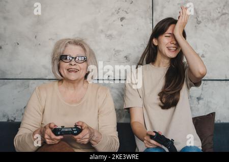 Ältere Frau und junge Frau, die Spaß beim Spielen von Videospielen zu Hause haben. Frohe Familie. Spaß Familie.Glückliche Familie. Lustige Familie. Stockfoto