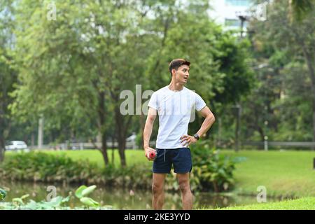 Junger, gutaussehender, sportlicher Mann, der sich nach dem Joggen im Park ausruhte. Gesundes Lifestyle-, Workout- und Wellness-Konzept Stockfoto