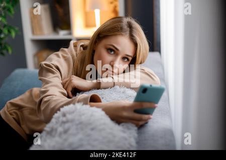 Blonde mit Smartphone auf dem Sofa Stockfoto