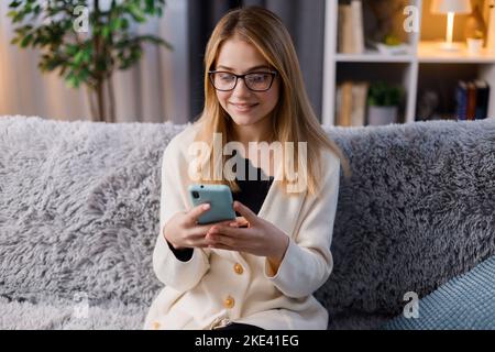 Frau mit Smartphone auf sofa Stockfoto