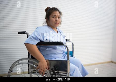 Asiatische fette Frau Patientin sitzt auf einem Rollstuhl, Knieschmerzen, übermäßiges Gewicht, Gesundheitskonzept. Stockfoto