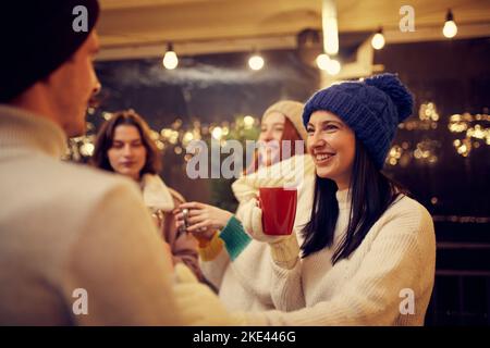 Neue Bekanntschaften bei Weihnachtsfeiertagen und Partys. Glücklicher Mann und Mädchen bei romantischen Dating mit heißen Getränken. Konzept von Emotionen, Urlaub, Liebe Stockfoto