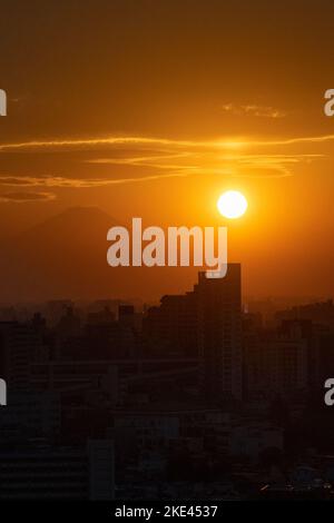 Tokio, Japan. 10.. November 2022. Die Sonne untergeht über Mt. Fuji (å¯Œå£«å±±), ein aktiver Stratovulkan am Feuerring des Pazifischen Ozeans, der zuletzt vor über 300 Jahren ausbrach, wobei die städtische Skyline von Tokio im Vordergrund von Kita City (åŒ-åŒº) aus gesehen wurde. Der Vulkan, auch bekannt als Fujisan, wird wegen seiner Schönheit bewundert und ist ein wichtiges Touristen- und Wanderziel. Das Zentrum von Tokio ist etwa 100 Kilometer vom Mt. Fuji und der Berg ist der siebthöchste Gipfel einer Insel auf der Erde.Japan hat vor kurzem wieder für den Tourismus nach mehr als zwei Jahren Reiseverbote aufgrund der Stockfoto