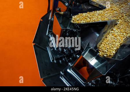 Eine industrielle Mehrkopf-Wägemaschine, die Erbsen-Portionen für die Verpackung vorbereitet. Das Foto wurde unter natürlichen Lichtbedingungen aufgenommen. Stockfoto