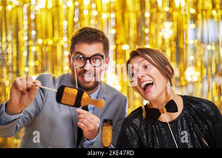 Pärchen über Gold mit Fotokabinen-Accessoires auf Party Stockfoto
