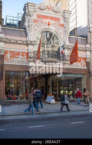 Die Besucher der Old Bond Street kommen am Eingang zur Royal Arcade vorbei Stockfoto