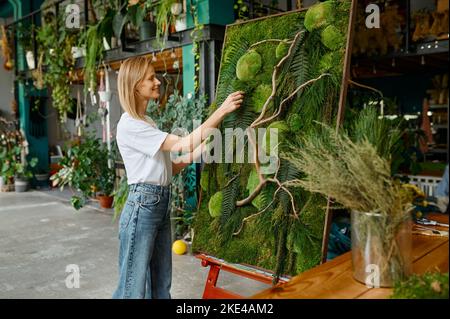 Junge glücklich Floristen Dekorator Anlage Moos Panel zu schaffen Stockfoto