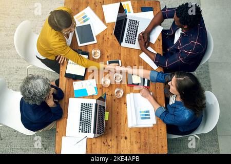 Waren sich hier alle einig. Ein Team von Kreativen, die sich gegenseitig die Hände über einen Tisch schüttelten, hat eine Aufnahme in einem hohen Winkel gemacht. Stockfoto