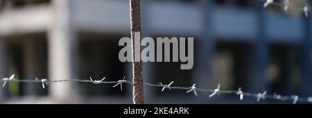 Stacheldrahtzaun vor dem Gefängnisgebäude in der Nähe Stockfoto
