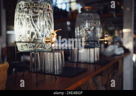 Zwei Glasdispenser mit Metallhahn und Deckel auf der Sommerparty. Stockfoto