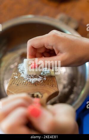 Eine Kokosnuss in eine Schüssel reiben. Stockfoto