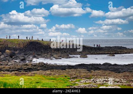 Touristen klettern auf den uralten Basaltsäulen des Giant's Causeway UNESCO-Weltkulturerbes, Causeway Coast, County Antrim, Nordirland Stockfoto