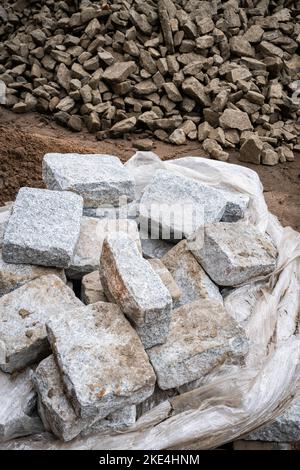 Eine Palette belgischer Bausteine auf einer Baustelle mit zerkleinertem Gestein im Hintergrund Stockfoto