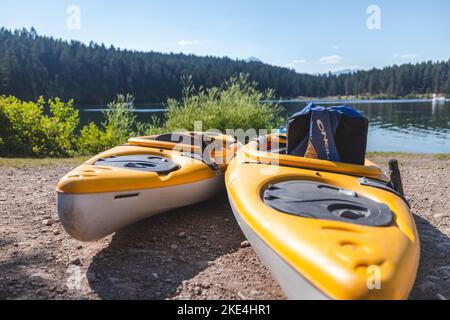 Eine Nahaufnahme von zwei orangefarbenen Kajaks am Ufer eines Sees in Radium, Kanada Stockfoto