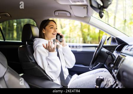 Geschäftsfrau Multitasking während der Fahrt, Kaffee trinken und reden am Telefon Stockfoto