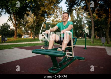 Guy Training in Outdoor-Fitness-Studio auf Rudergerät Stockfoto