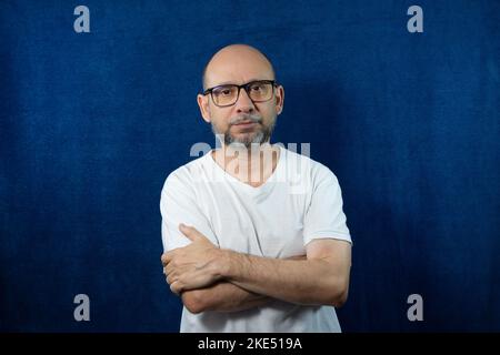 Ein Porträt eines bärtigen kahlen Mannes vor blauem Hintergrund. Stockfoto