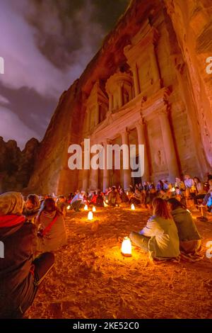 Touristen, die vor der Schatzkammer in Petra Jordan sitzen und nachts von Kerzen erleuchtet werden Stockfoto