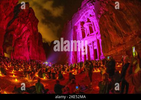 Touristen, die vor der Schatzkammer in Petra Jordan sitzen und nachts von Kerzen erleuchtet werden Stockfoto