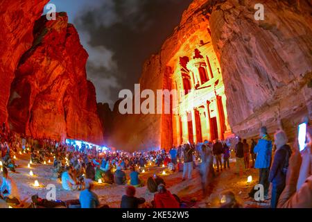 Touristen, die vor der Schatzkammer in Petra Jordan sitzen und nachts von Kerzen erleuchtet werden Stockfoto