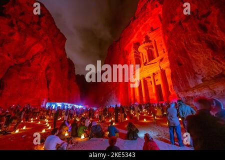 Touristen, die vor der Schatzkammer in Petra Jordan sitzen und nachts von Kerzen erleuchtet werden Stockfoto