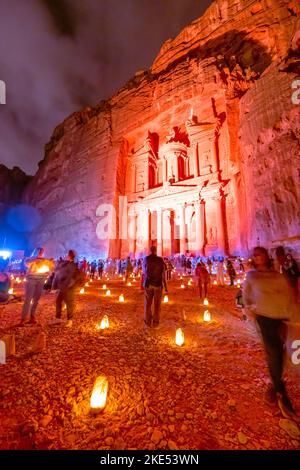 Touristen, die vor der Schatzkammer in Petra Jordan sitzen und nachts von Kerzen erleuchtet werden Stockfoto