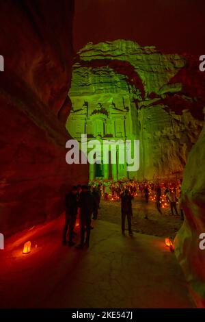 Touristen, die vor der Schatzkammer in Petra Jordan sitzen und nachts von Kerzen erleuchtet werden Stockfoto