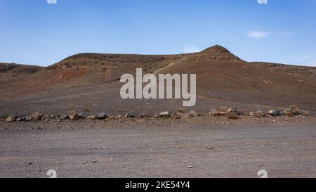 Leere Wüste in einer trockenen Landschaft in Richtung vulkanischer Berge in der Nähe von Playa Mujeres und der Papagayo-Küste, Lanzarote, Spanien. Stockfoto