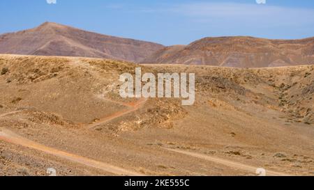 Karge Vulkanlandschaft mit Vulkanen am Horizont auf Lanzarote, Kanarische Inseln, Spanien. Stockfoto