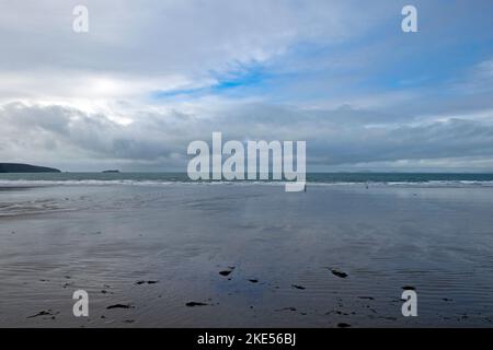 Leerer Strand in Broadhaven Person führt einen Hund an einem regnerischen Novembertag im Winter 2022 an der Pembrokeshire Küste in West Wales UK KATHY DEWITT Stockfoto