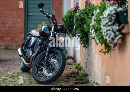 Kuldiga, Lettland - 6. November 2022: Klassisches Motorrad Triumph Bonneville T100 Schwarz im Innenhof der Altstadt Stockfoto