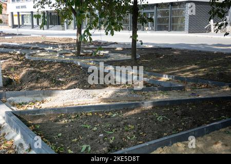 Bau eines Parkwegs. Grenzen entlang des Parkweges, Tropfbewässerungssystem zur Bewässerung der grünen Abdeckung im Parkbereich. Stockfoto