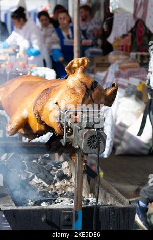 Ferkel am Spieß. Gegrilltes Schwein beim Street Food Festival. Gebratenes Schwein auf dem Regal. Essen. Selektiver Fokus Stockfoto