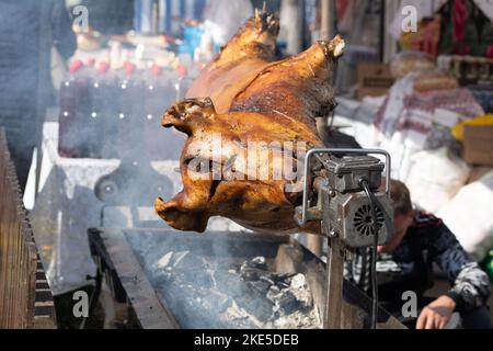 Ferkel am Spieß. Gegrilltes Schwein beim Street Food Festival. Gebratenes Schwein auf dem Regal. Essen. Stockfoto