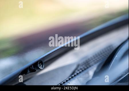 Scheibenwaschdüse unter der Motorhaube, mit der Flüssigkeit zum Reinigen von Glas auf ein Fahrzeug gesprüht wird. Stockfoto