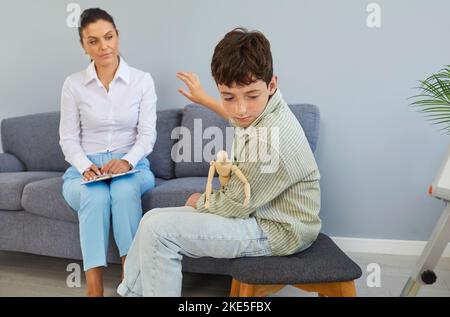 Verärgert preteen Junge wendet sich ab und weigert sich, in der Therapie-Sitzung mit Psychologen zu kommunizieren. Stockfoto