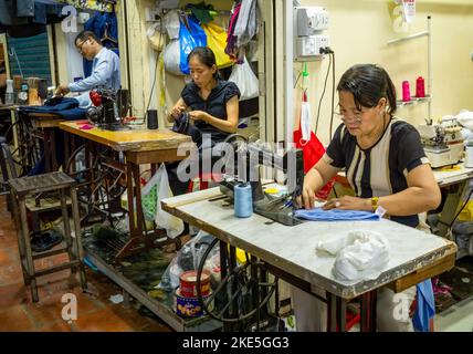 Schneider und Näherinnen arbeiten an ihren Nähmaschinen auf dem russischen Markt im Zentrum von Phnom Penh, Kambodscha. Stockfoto