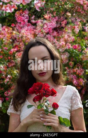 Dort steht eine romantisch aussehende Dame mit Rosenformen auf der Haut, in einem fröhlichen Look. Stockfoto