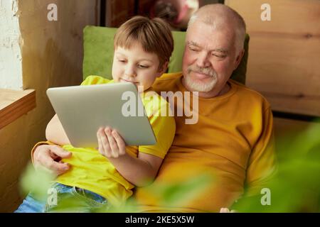 Glücklicher Großvater und Enkel verbringen Zeit zusammen zu Hause. Konzept von Emotionen, Familie, Glück, Pflege, Unterstützung und Freizeitaktivitäten Stockfoto