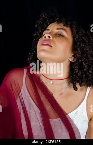 Nahaufnahme Porträt einer Frau mit transparentem Tuch auf schwarzem Hintergrund. Reife Frau. Selbstwertgefühl-Konzept. Stockfoto