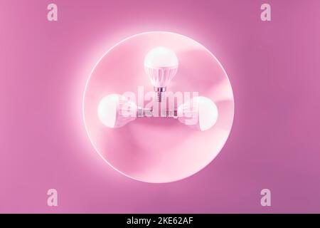 Drei leuchtende LED-Lichter auf einem weißen Teller, rosa Hintergrund. Energiesparende Technologie. Stockfoto