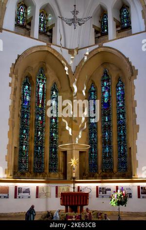 Krippengrotte unter einem Alten mit bunten Buntglasfenstern im Hintergrund, St. Wilfrid's Church, Harrogate, North Yorkshire, England, Großbritannien. Stockfoto