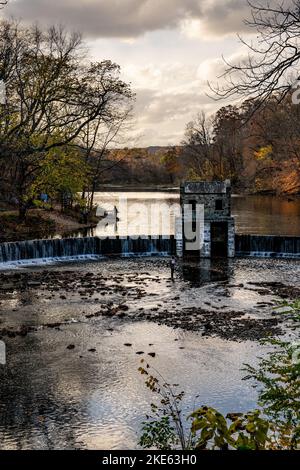 Morristown, NJ - USA - Nov 5, 2022 eine herbstliche vertikale Ansicht des historischen Speedwell-Staudamms aus Stein von New Jersey bei Sonnenuntergang. Fliegenfischer in der Vorbou Stockfoto