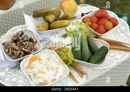 Essen auf dem Tisch. Gurken aus dem Garten. Gurken und Tomaten auf Tellern. Herzhaftes Mittagessen. Stockfoto