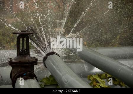 Ventil am Rohr. Rohrventil gerissen. Kochendes Wasser fließt aus der Pipeline. Stockfoto