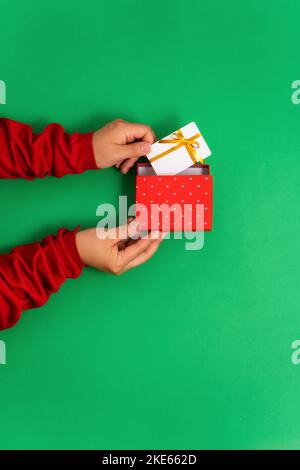 Weibliche Hände nehmen eine Bonus- oder Geschenk-Bankkarte-Vorlage aus einer Geschenkbox für Online-Dienste und Shopping Top-Ansicht, flach liegend Stockfoto